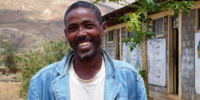 Ethiopian farmer Kiros Tesfaye, stands in front of his son’s school. 